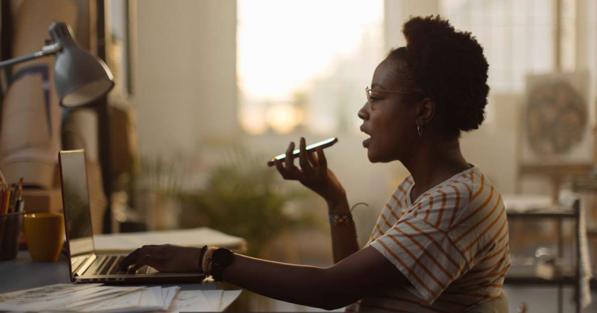 Une personne qui parle dans son téléphone en même temps qu'elle utilise son ordinateur portable