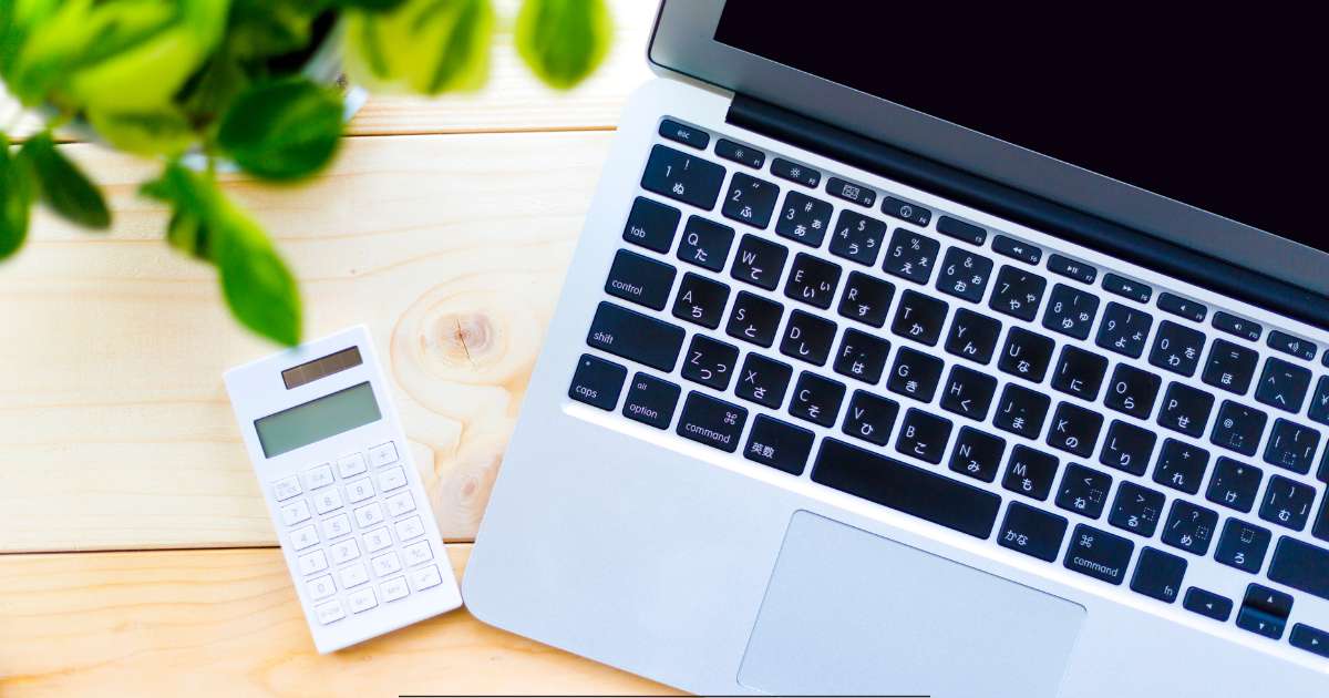 Un ordinateur, à droite et une calculatrice à gauche. On voir également une plante forte, la photo est prise de dessus.
