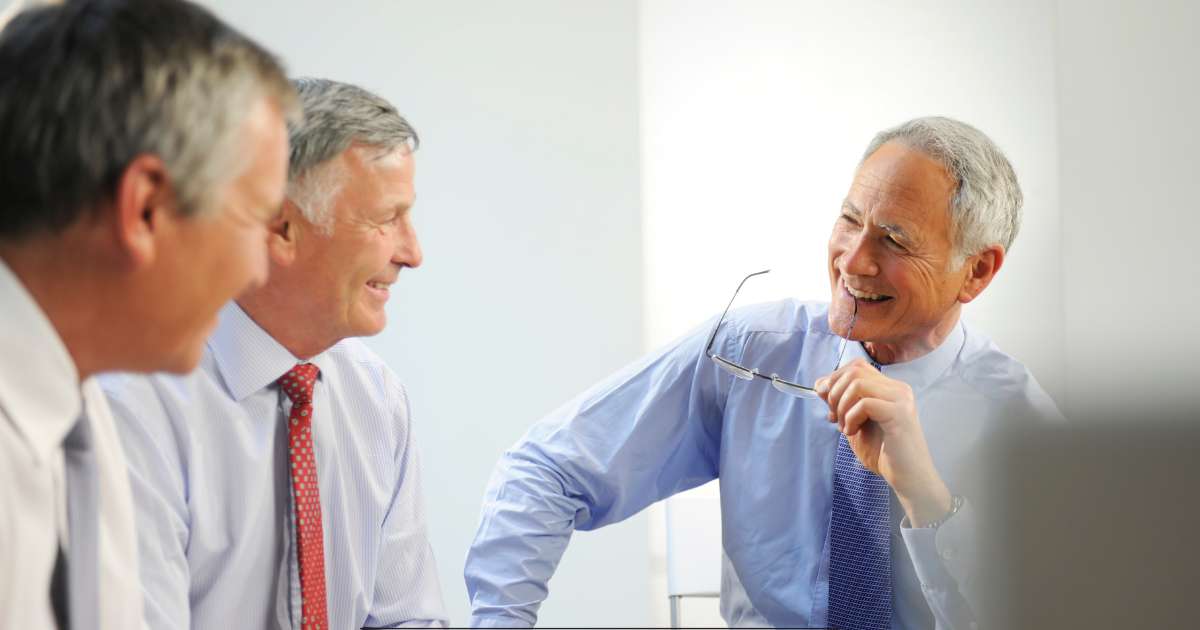 Trois hommes en cravate discutent ensemble.